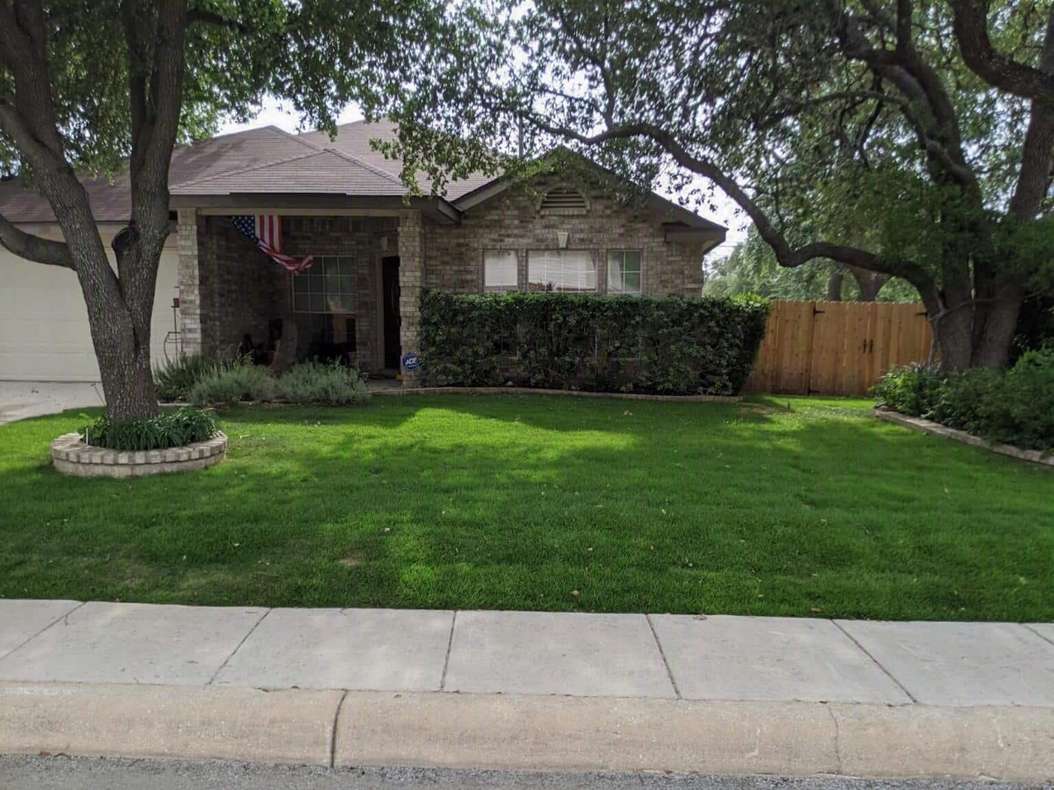 Freshly maintained lawn and live oaks at a North San Antonio home serviced by Encore Property Maintenance